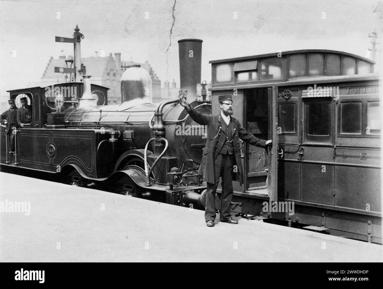 This train is now ready to depart Description: "Photograph of railway guard giving the signal to the engine driver." Photograph by RL Sirus. Date: 1884 sepia, train, transport, guard, railway, locomotive, railways, conductor, steamtrain, 1884 Stock Photo