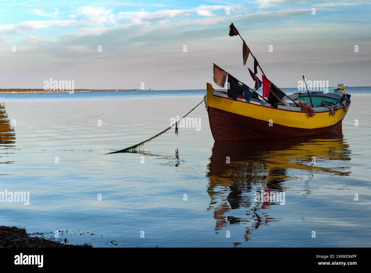 Wooden fishing boat moored at the shore, a landscape with calm water ...
