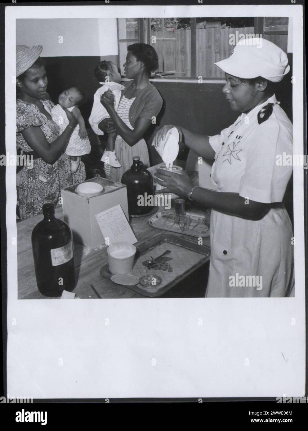 Description: Barbados. 'A mother with her baby is issued with milk at Blackrock Baby Welfare Clinic'. Photograph No D 77080 Official Barbados photograph compiled by Central Office of Information. Publicity statement on reverse. Location: Barbados Date: 1955 Mar barbados, caribbean, caribbeanthroughalens Stock Photo