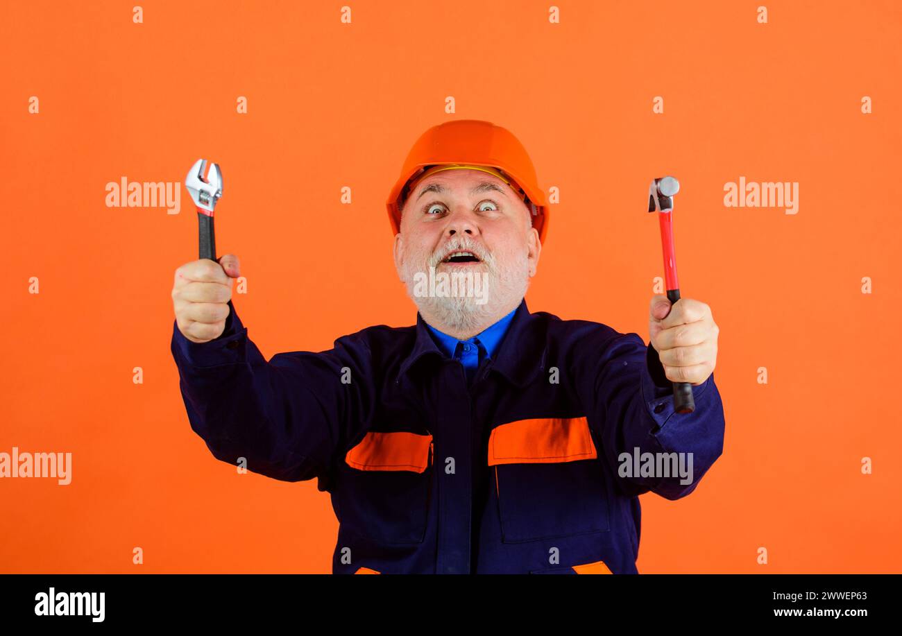 Surprised male builder in protective hard hat with adjustable wrench ...