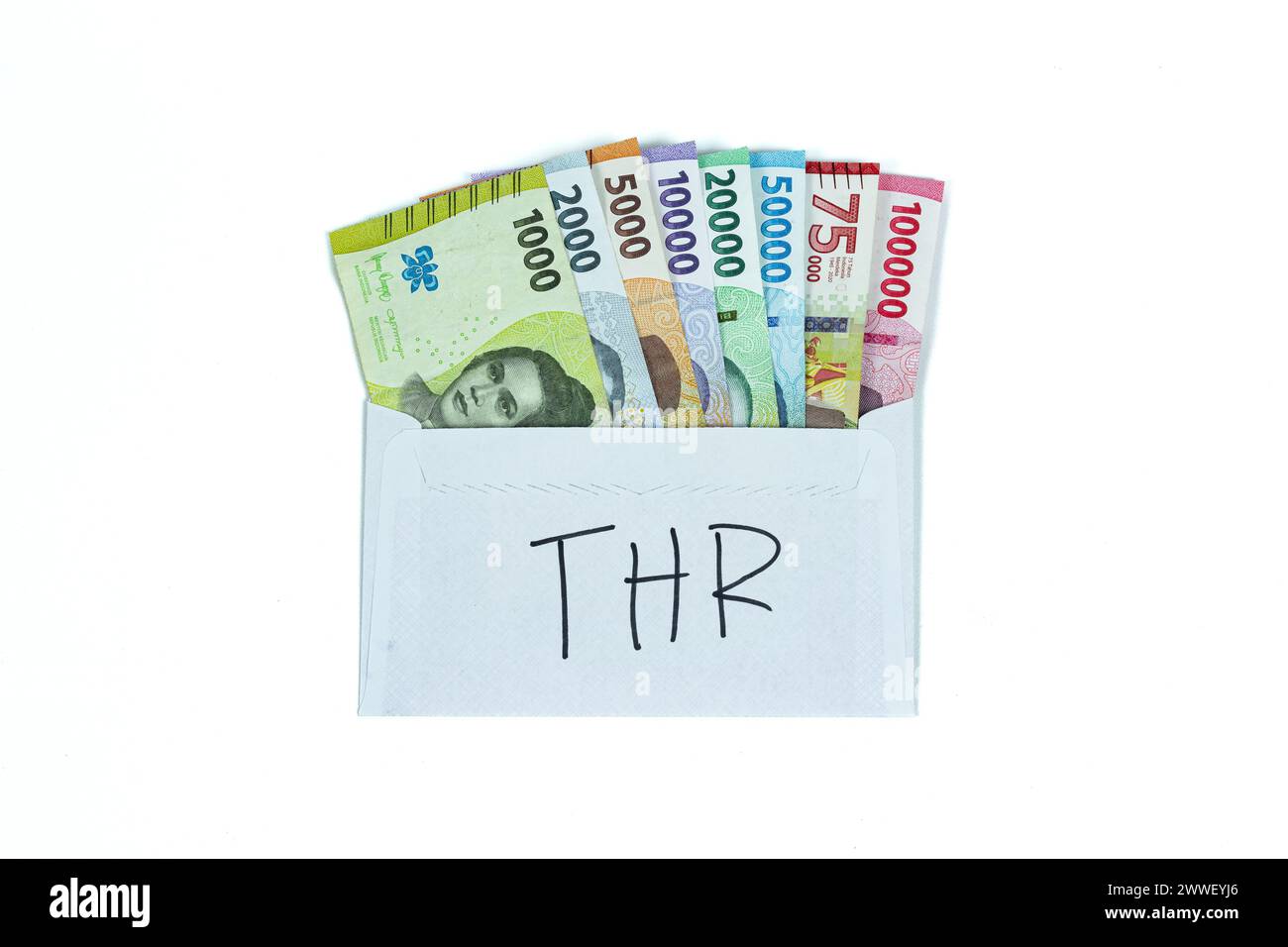 Indonesian currency. Stack of Rupiah or IDR banknotes inside white envelope with THR Text. THR is holiday allowance on Eid al-Fitr or Lebaran days. Stock Photo