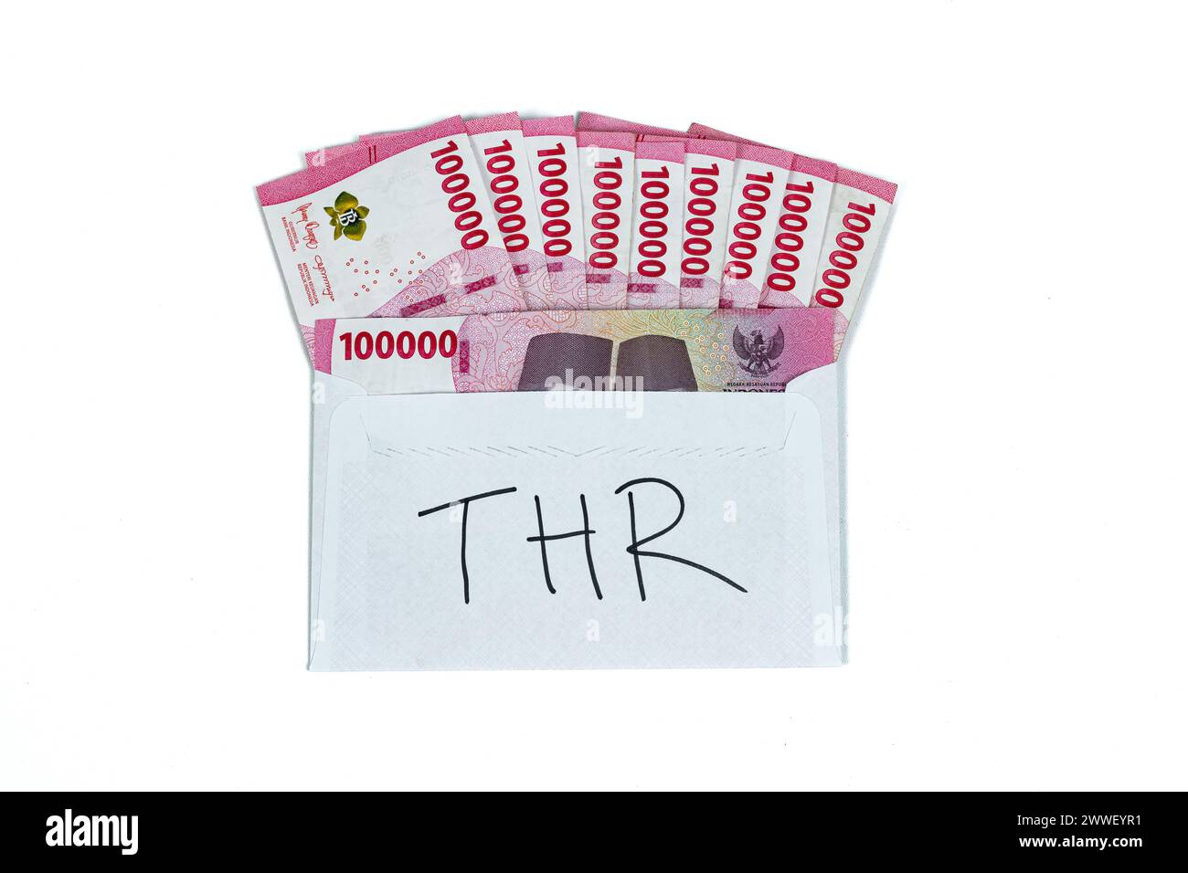 Indonesian rupiah currency. White envelope with THR Text containing stack of IDR 100,000 cash.THR is holiday allowance on Eid al-Fitr or Lebaran days. Stock Photo