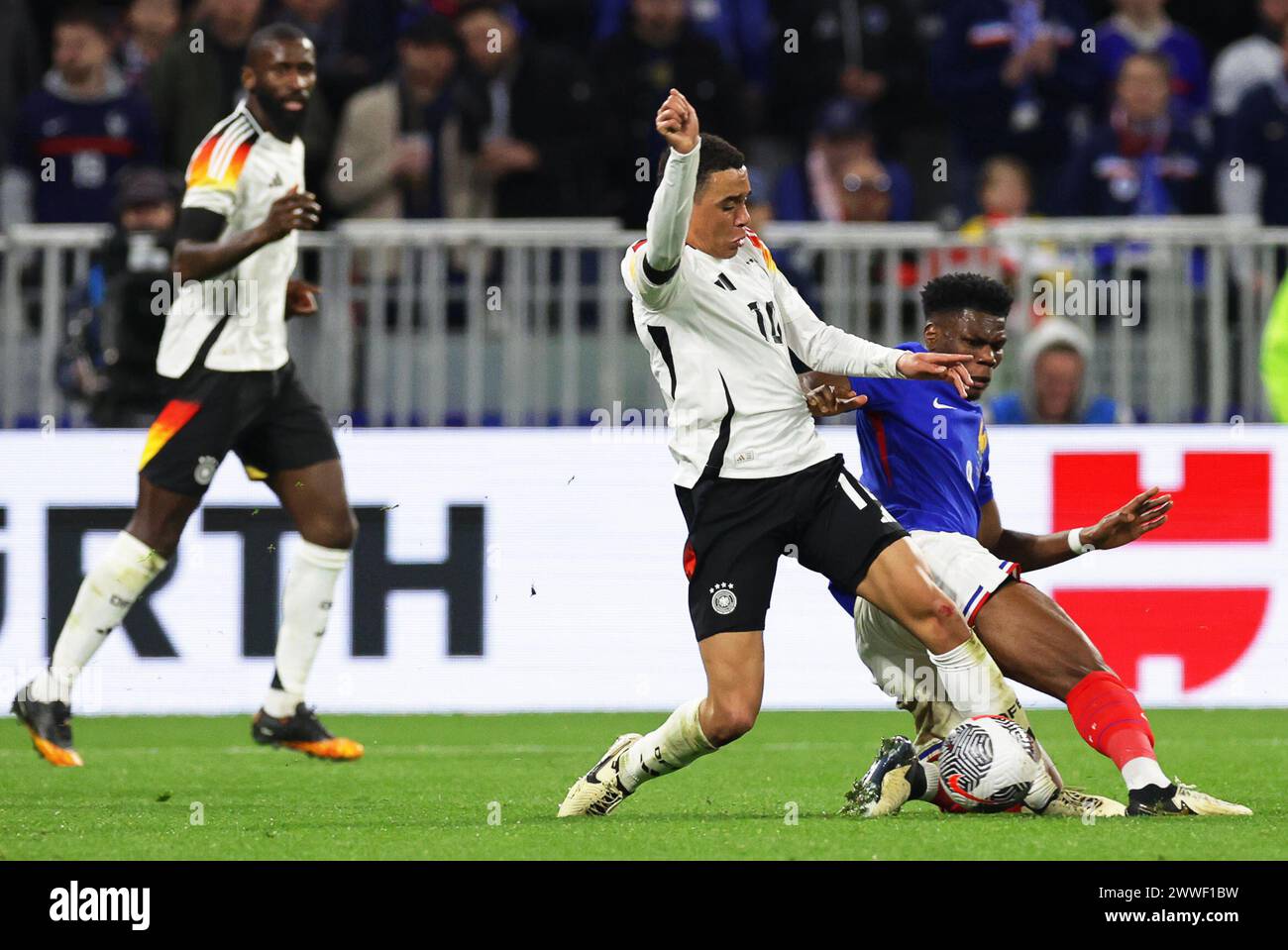 Lyon, France. 23rd Mar, 2024. Soccer: International match, France - Germany, Groupama Stadium. Germany's Jamal Musiala (center) and France's Aurelien Tchouameni (right) fight for the ball. Credit: Christian Charisius/dpa/Alamy Live News Stock Photo