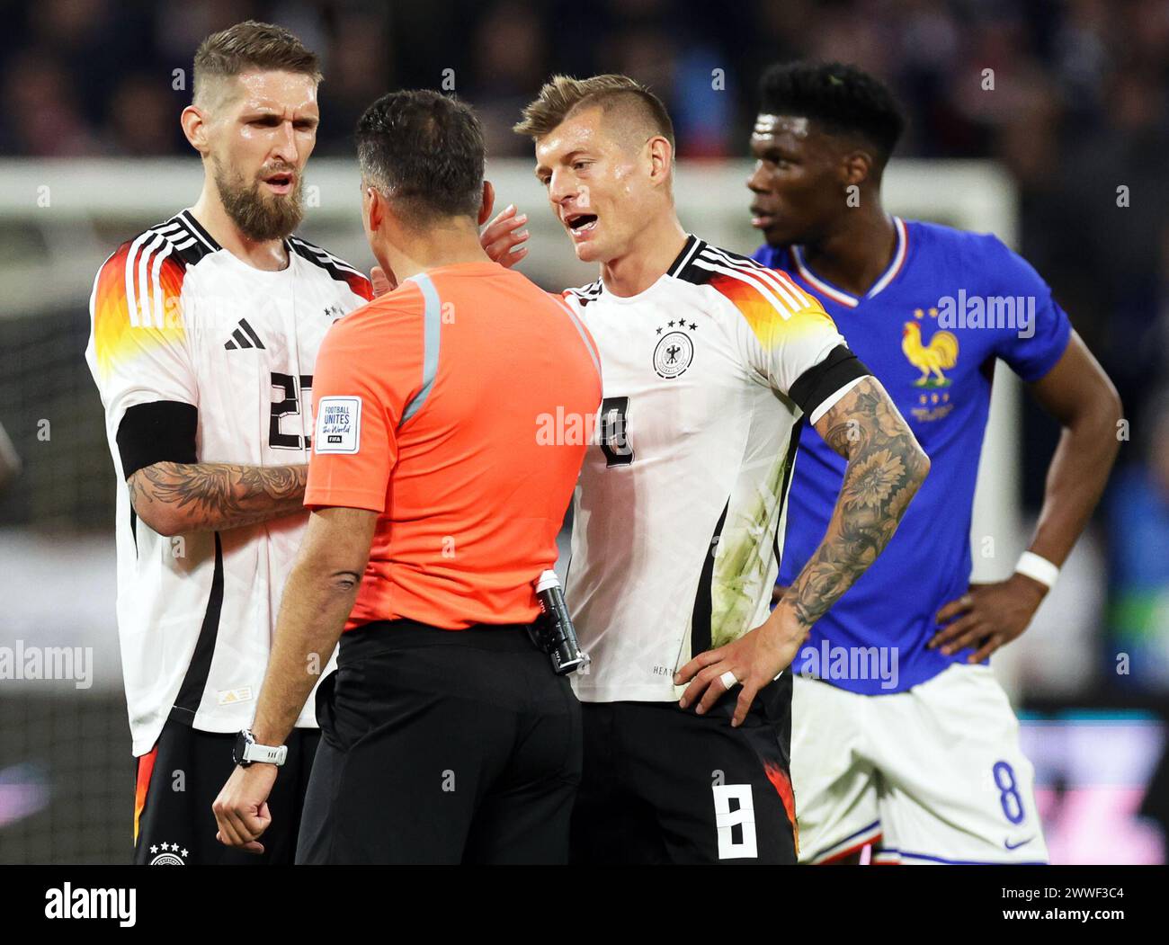 Lyon, France. 23rd Mar, 2024. Soccer: International match, France - Germany, Groupama Stadium. Germany's players Robert Andrich (l) and Toni Kroos (2nd from right) discuss with referee Jesus Gil Manzano (2nd from left) from Spain. Credit: Christian Charisius/dpa/Alamy Live News Stock Photo