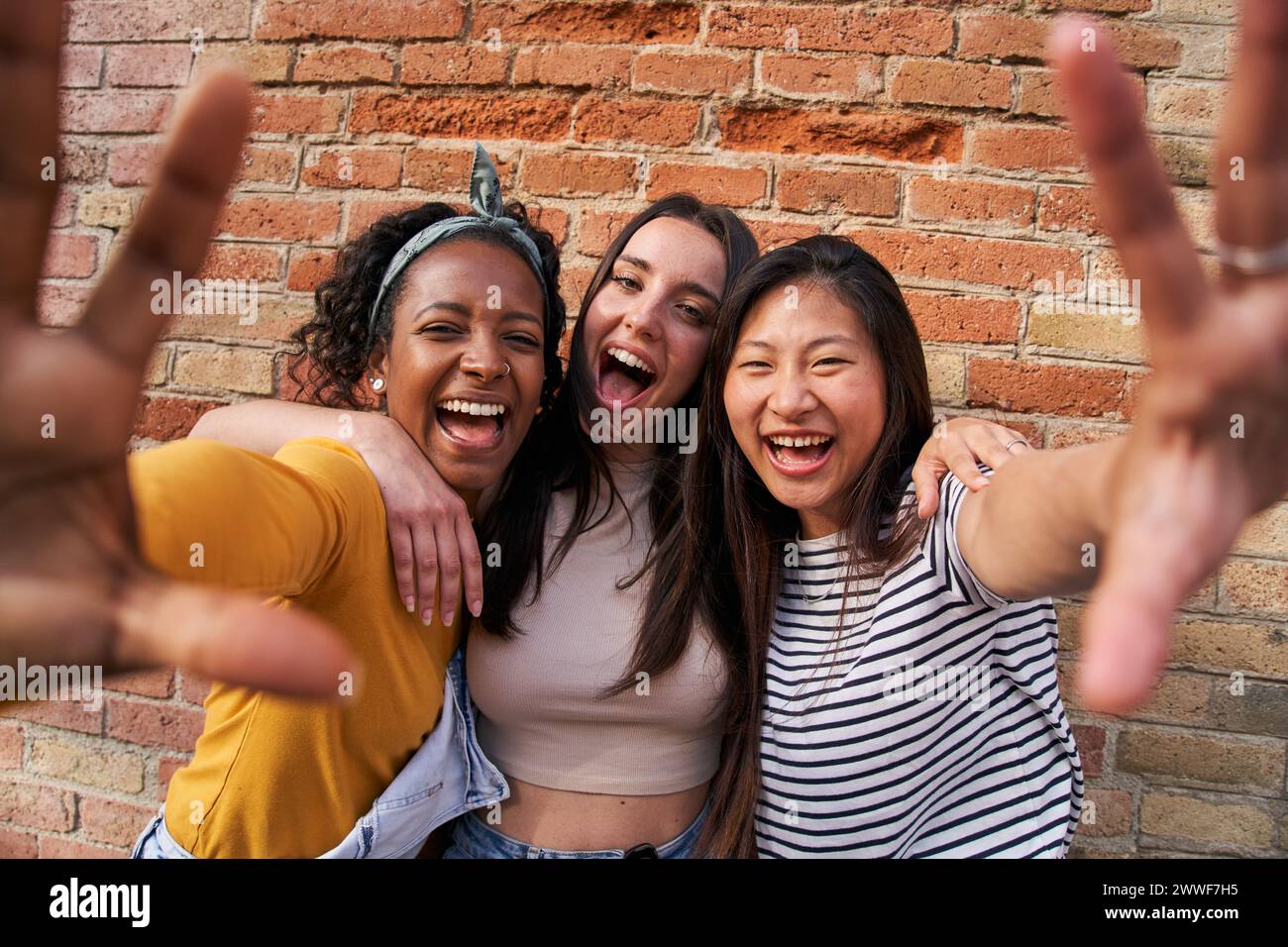 Portrait three excited multiracial joyful girls outdoors. Young females having fun posing for photo. Stock Photo
