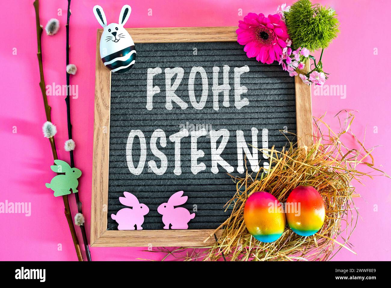 Augsburg, Bavaria, Germany - March 23, 2024: Happy Easter Greeting on a blackboard surrounded by Easter decorations with an Easter nest and colorful eggs. PHOTOMONTAGE *** Frohe Ostern Gruß auf einer Tafel umgeben von Osterdekoration mit Osternest und bunten Eiern. FOTOMONTAGE Stock Photo