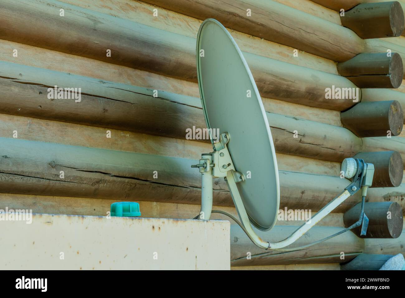 Satellite television receiver dish mounted on exterior wall of log cabin in South Korea Stock Photo