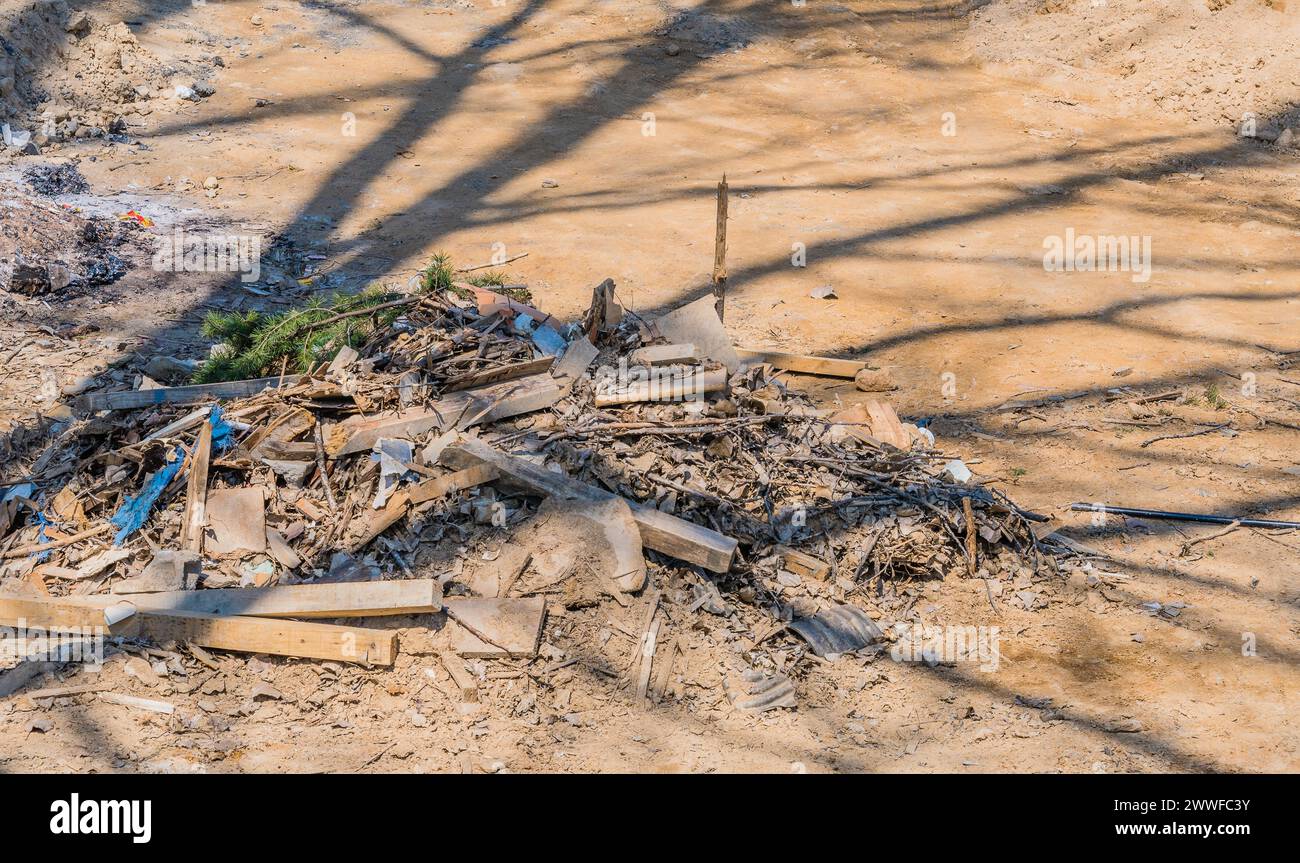 Pile of construction debris and wood scraps shadowed by a tree, in ...
