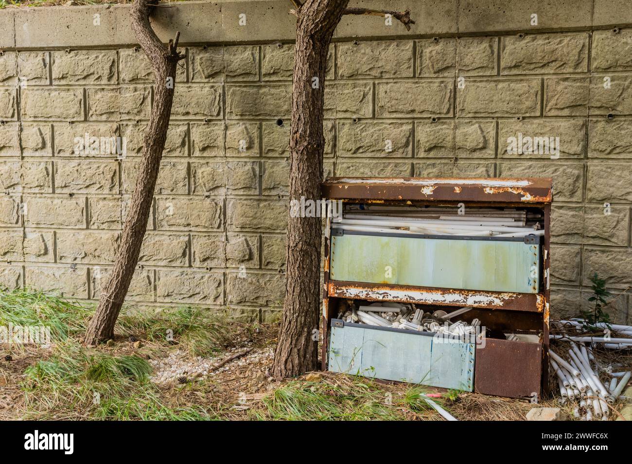 A decaying metal filled with expired light bulbs against a wall