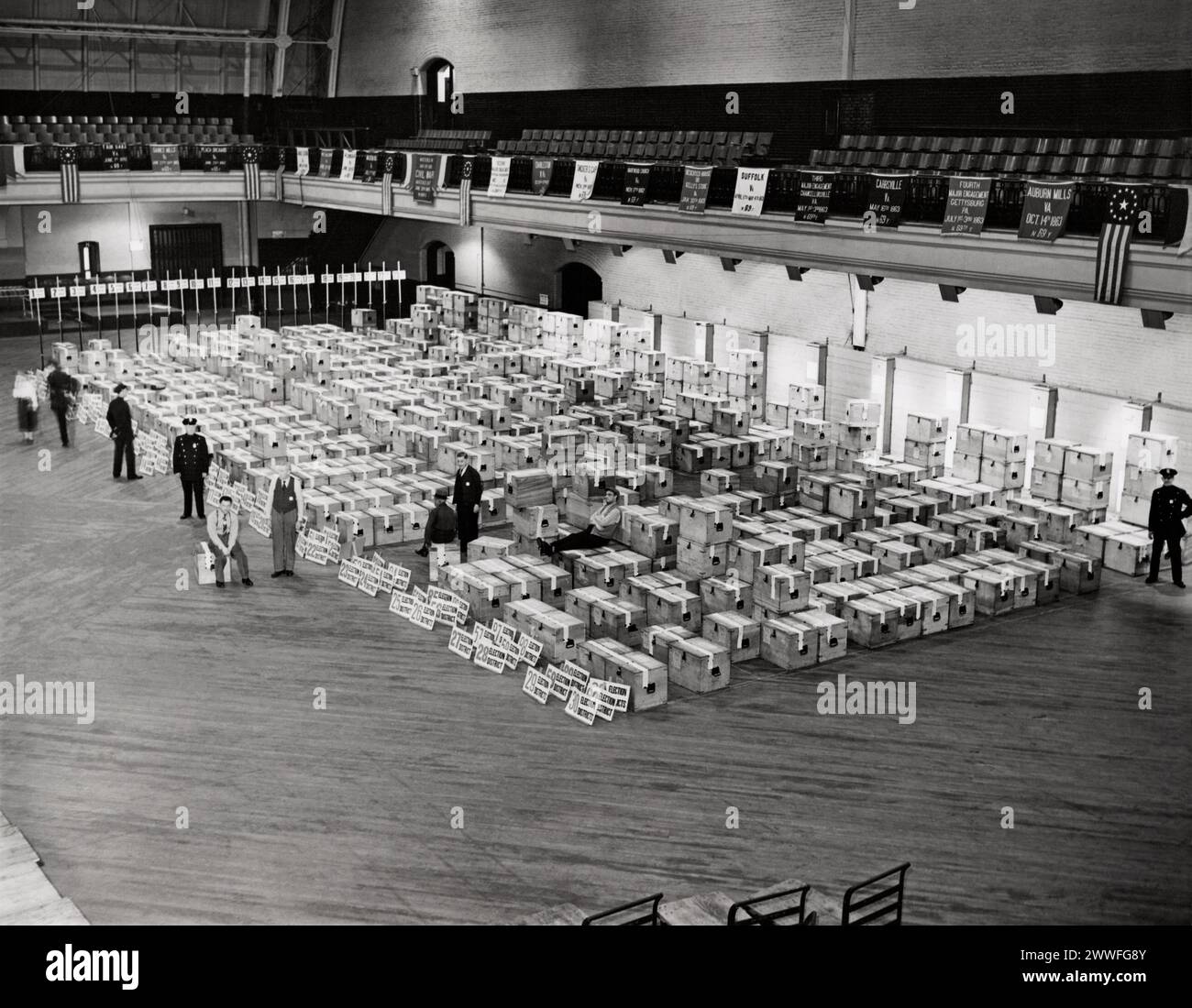 New York, New York, March 11, 1943 New York City police stand guard as hundreds of ballot boxes, sealed with tape, rest on the floor of the 69th armory to await counting. The ballots inside will determine the city's new city council. Stock Photo
