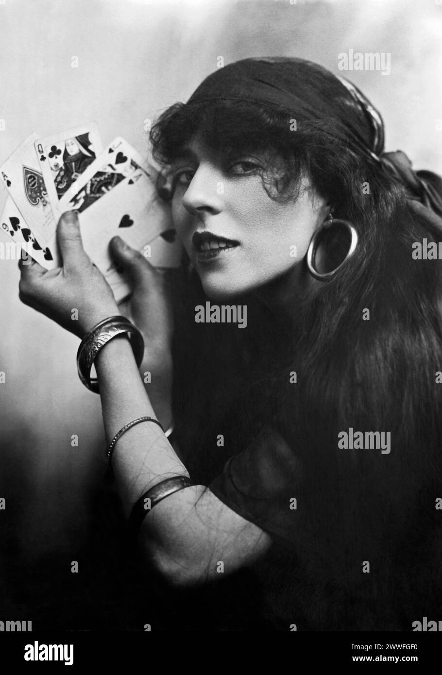 United States   c 1912 Silent film actress Florence Lee appearing as a fortune teller wearing a headscarf with hoop earings, bangles and holding a deck of cards in her hand. Stock Photo