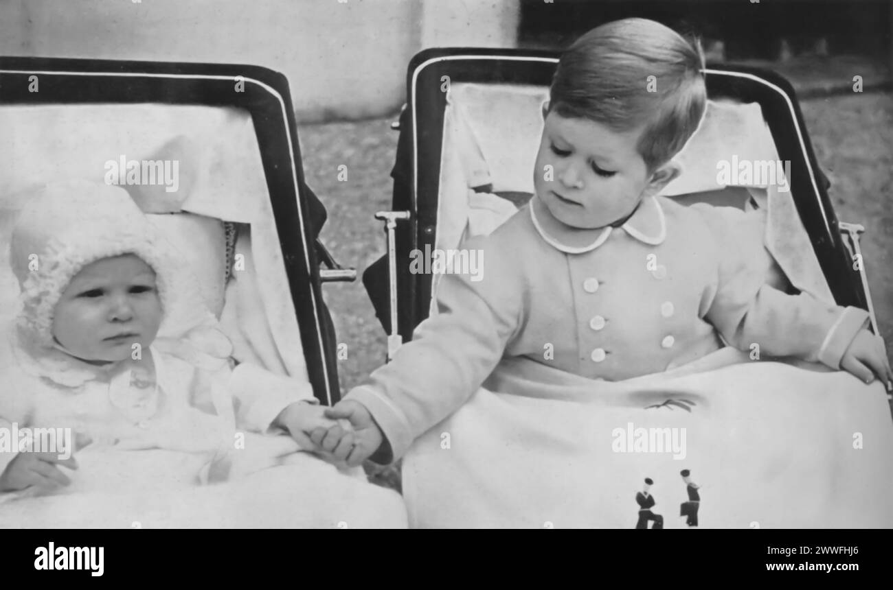 A photograph from 1951 shows a young Prince Charles III and Princess Anne in their prams (baby strollers), with Charles seen holding his younger sister's hand. This image captures a touching moment between the future king and his sister. Stock Photo