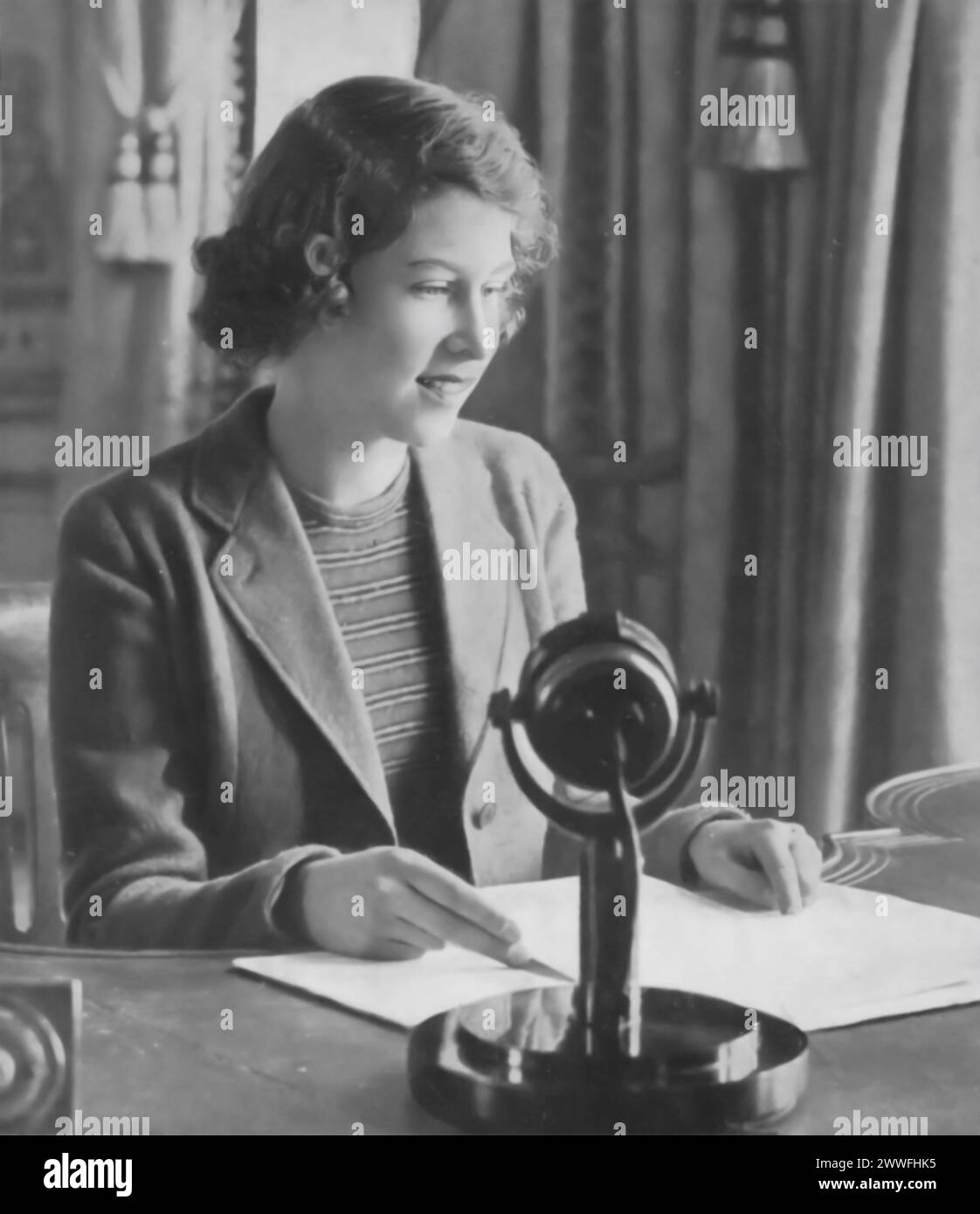 A photograph captures Princess Elizabeth II during her first radio broadcast in 1940, addressed to the 'Empire Children.' This historic moment showcases the young princess stepping into a public role, reaching out to children across the British Empire during a time of global conflict, marking her early contribution to royal duties and the war effort. Stock Photo