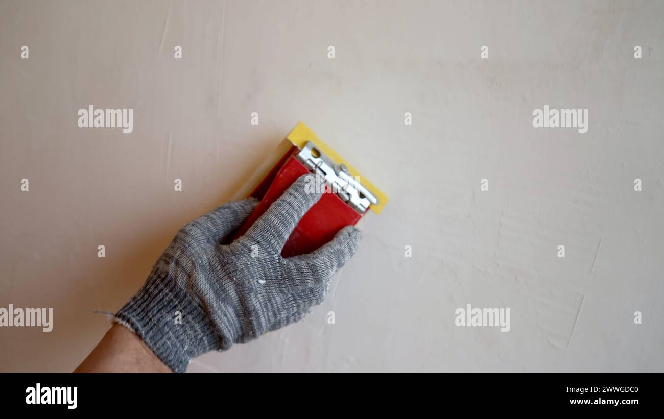 Peeling off uneven surfaces on a putty wall, sanding the freshly