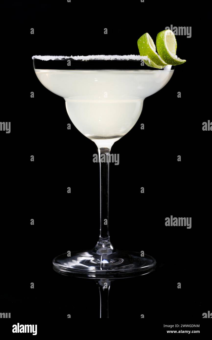 Classic margarita cocktail garnished with lime zest on salt rim, isolated on black reflective surface background Stock Photo