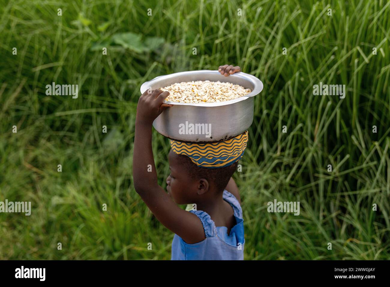 A child carries maize in the flooding-prone regions around Lake Chilwa in the Machinga district of Malawi. Villages in these communities have not recovered completely from Cyclone Freddy, and are doing what they can to prepare for next time. Picture date: Tuesday March 5, 2024. Stock Photo