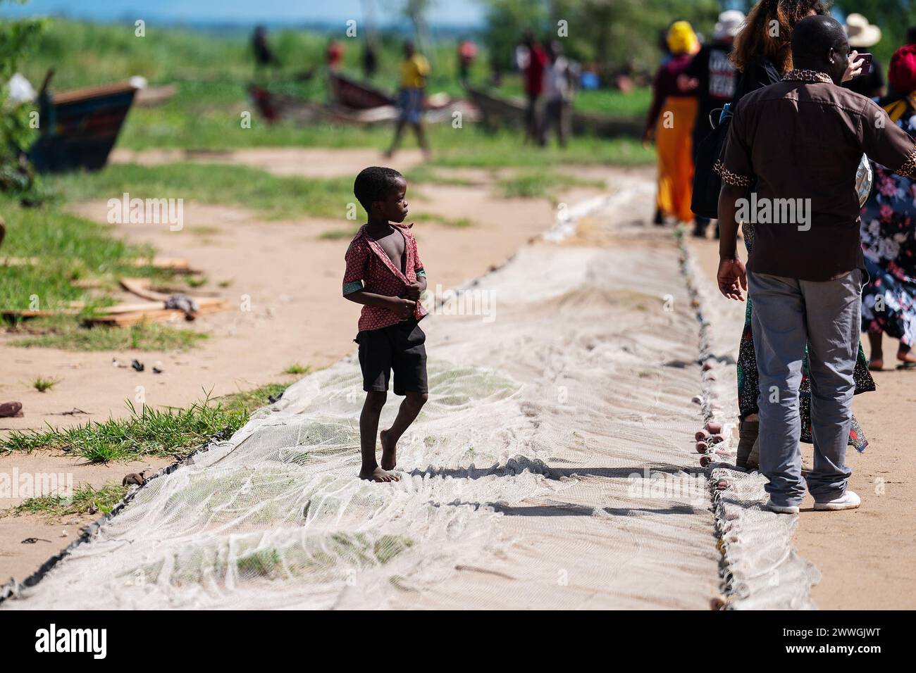 A boy walks on a fishing net on the shores of Lake Chilwa in the Machinga district of Malawi. Trocaire and its local groups are helping locals patrol Lake Chilwa to ensure there is no illegal fishing. In 2015, the lake completely dried out because of climate change, which led to the loss of most species of fish, putting more pressure on another vital food source. Picture date: Tuesday March 5, 2024. Stock Photo