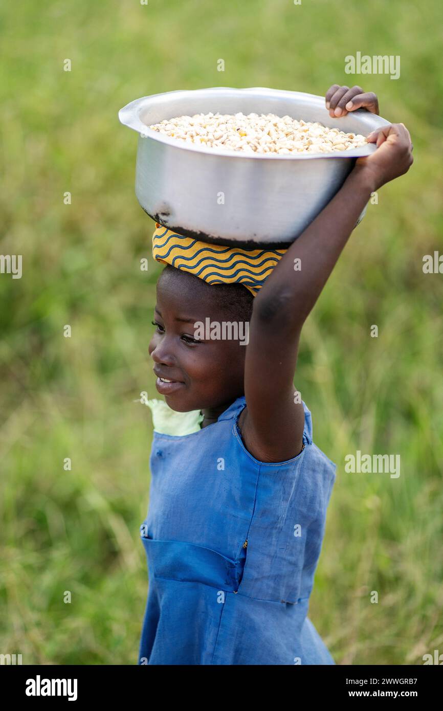 A child carries maize in the flooding-prone regions around Lake Chilwa in the Machinga district of Malawi. Trocaire is training farmers in new diverse crops that can tolerate weather extremes better than maize can. Picture date: Tuesday March 5, 2024. Stock Photo