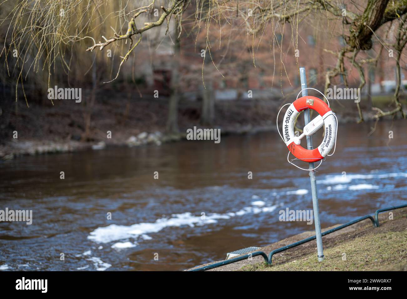 Lifebuoy on the river bank in city park Strömparken during spring in Norrköping. Norrköping is a historic industrial town in Sweden Stock Photo