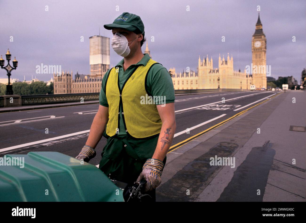 1990s London street cleaners working an early morning shift on Westminster Bridge, wearing protective clothing and a dust face mask, working at a so called 'dirty job' with recently introduced mechanical hoover, that sucks up waste and rubbish cleaning the street. Westminster, London, June 1992. England HOMER SYKES Stock Photo
