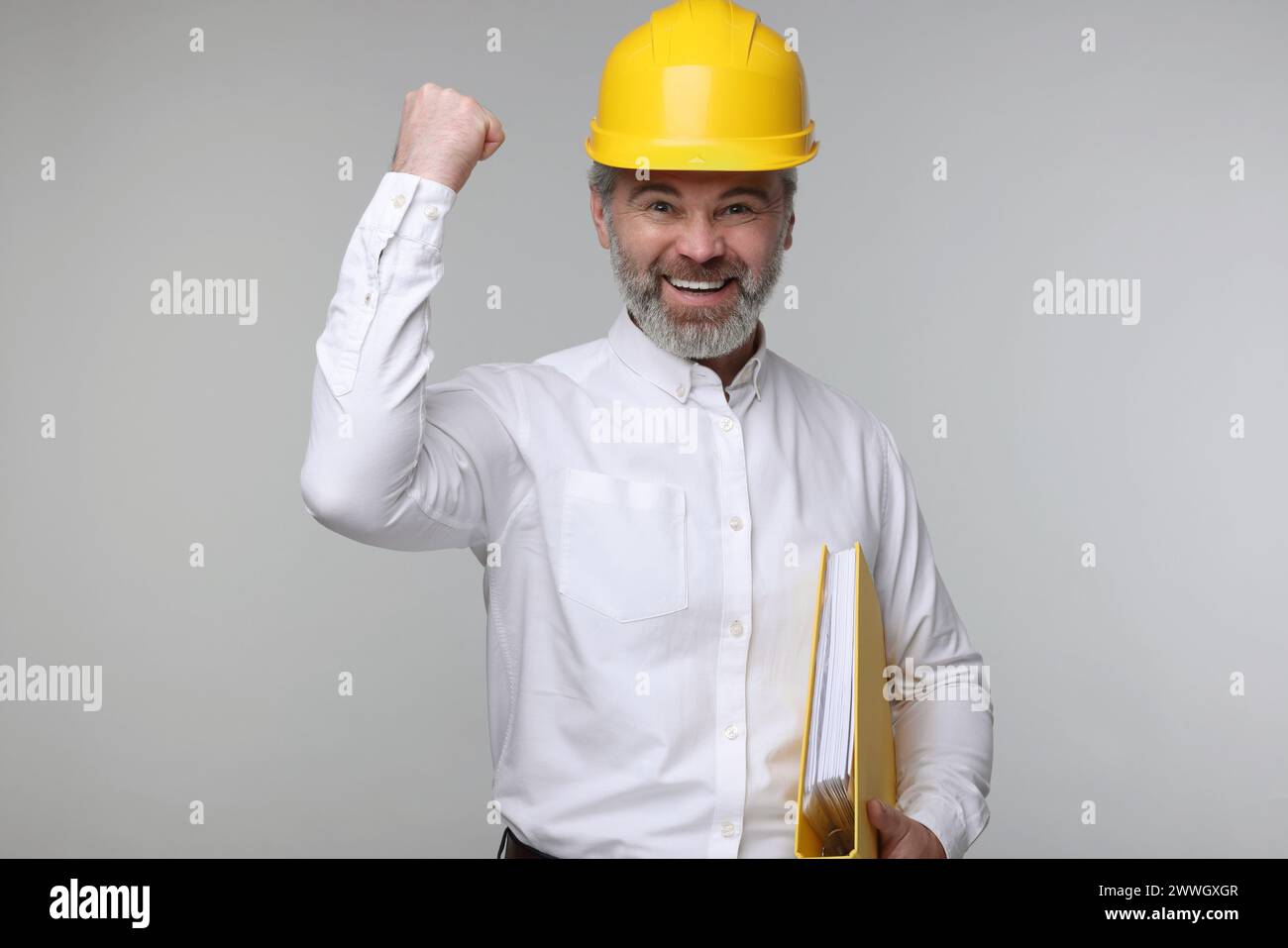 Architect in hard hat holding folder on grey background Stock Photo