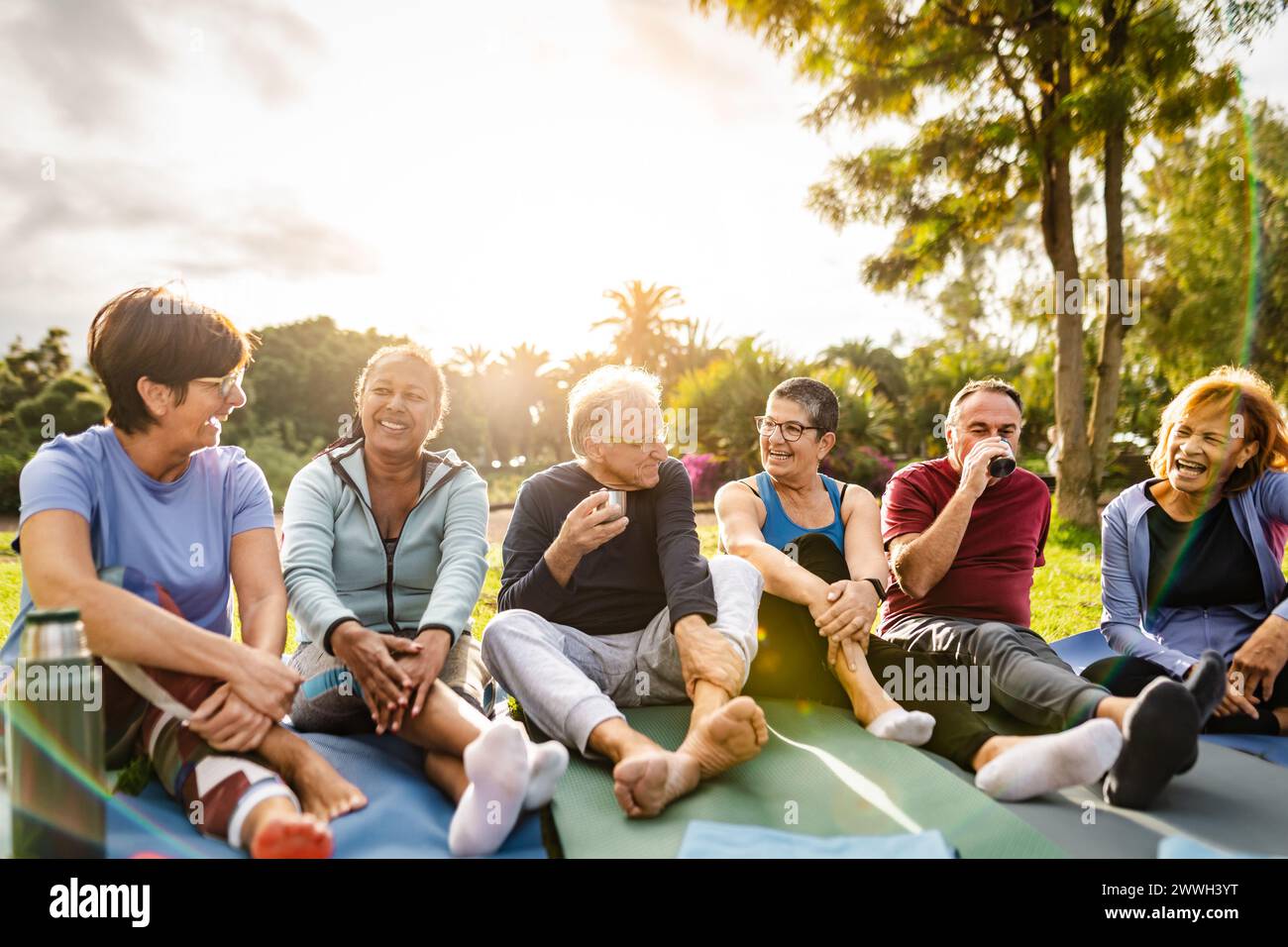 Happy multiracial senior friends drinking a tea after workout activities in a park Stock Photo