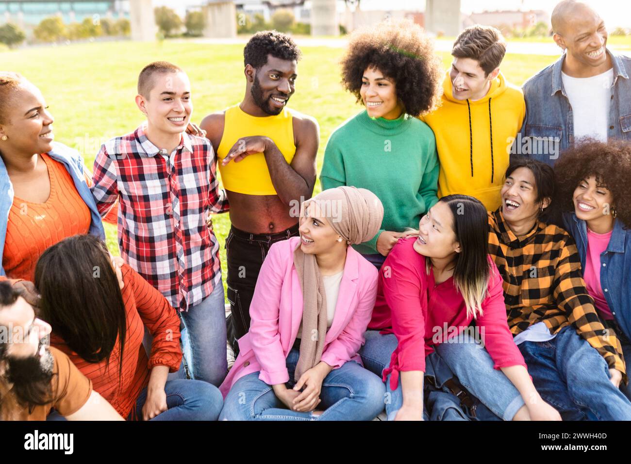 Happy young multiracial people having fun sitting on grass in a public park - Diversity and friendship concept Stock Photo