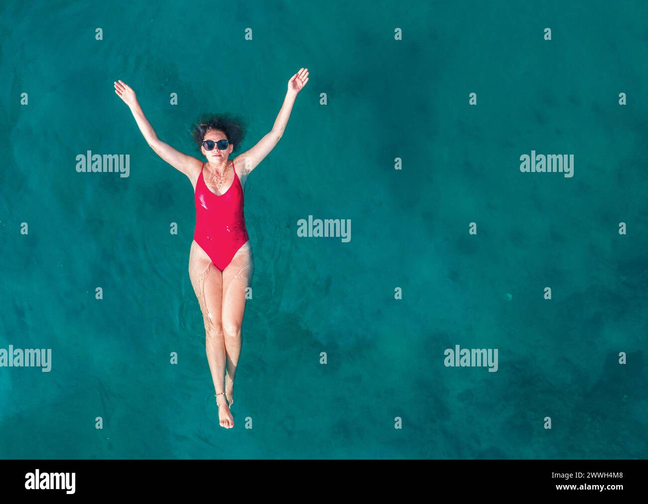 Aerial View of a Woman in Red Swimsuit Floating Serenely on the Crystal ...