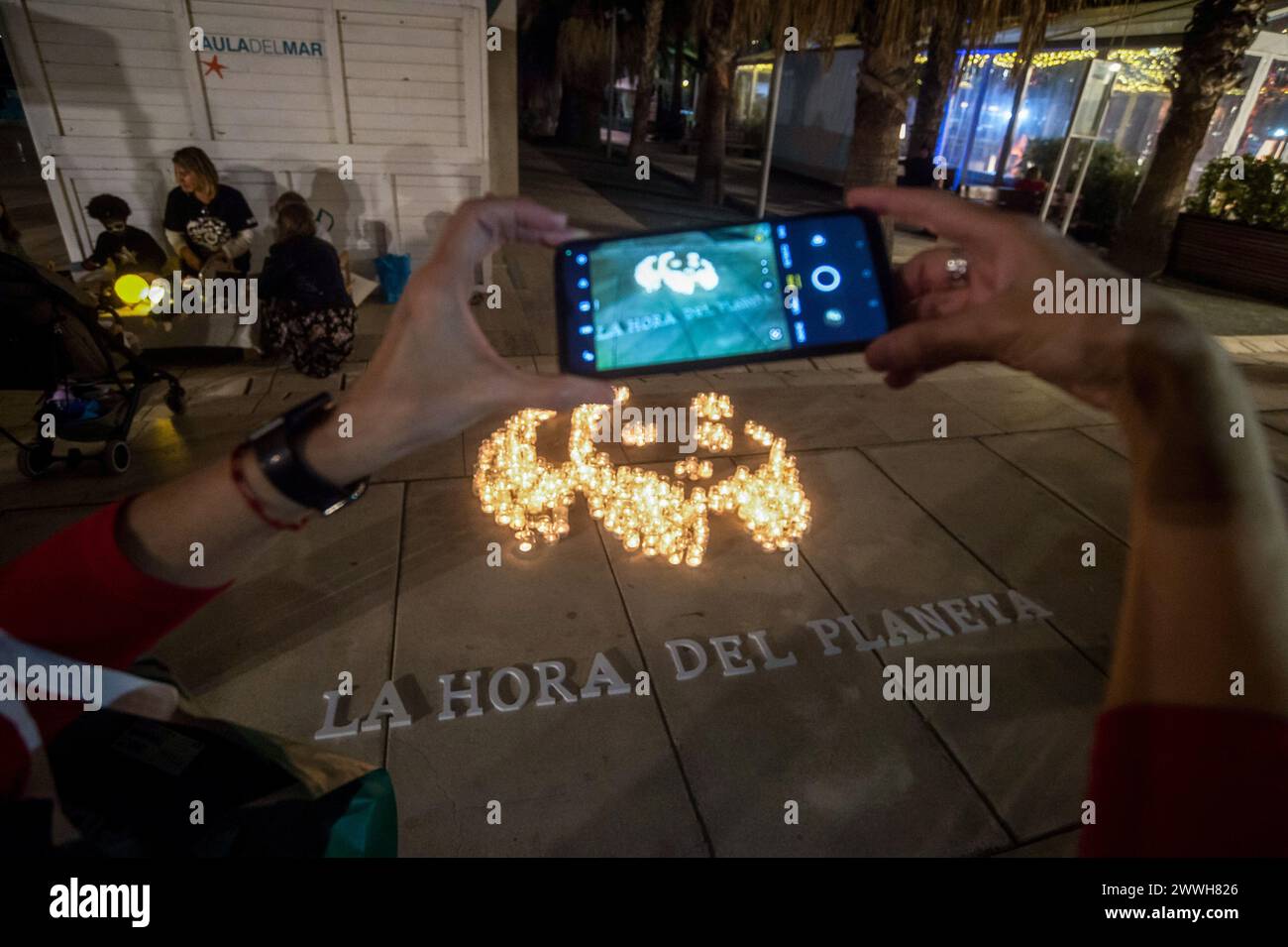 A member of the World Wildlife Foundation (WWF) is seen taking a photo of a mosaic made with candles depicting a panda during the Earth Hour in the centre of Malaga. The figure made with candles is a panda, the symbol of the WWF. Thousands of cities around the world switched off their electric lights during the Earth Hour to highlight the dangers of climate change. The figure made with candles is a panda, the symbol of the WWF. Thousands of cities worldwide switched off their electric lights during Earth Hour to highlight the dangers of climate change. Stock Photo
