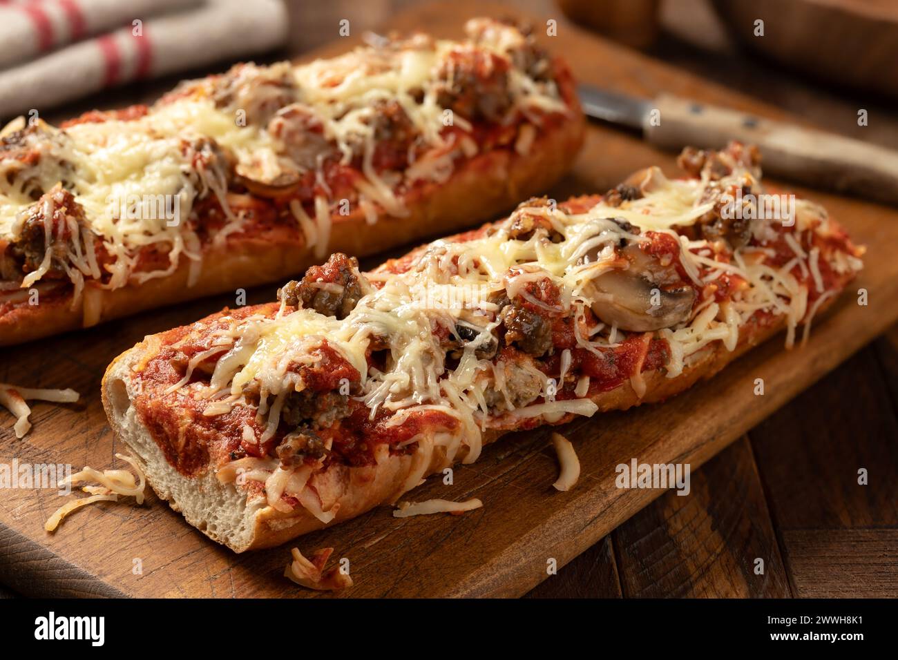 Pizza bread made with sausage, mozzarella cheese and tomato sause on an old wooden cutting board Stock Photo