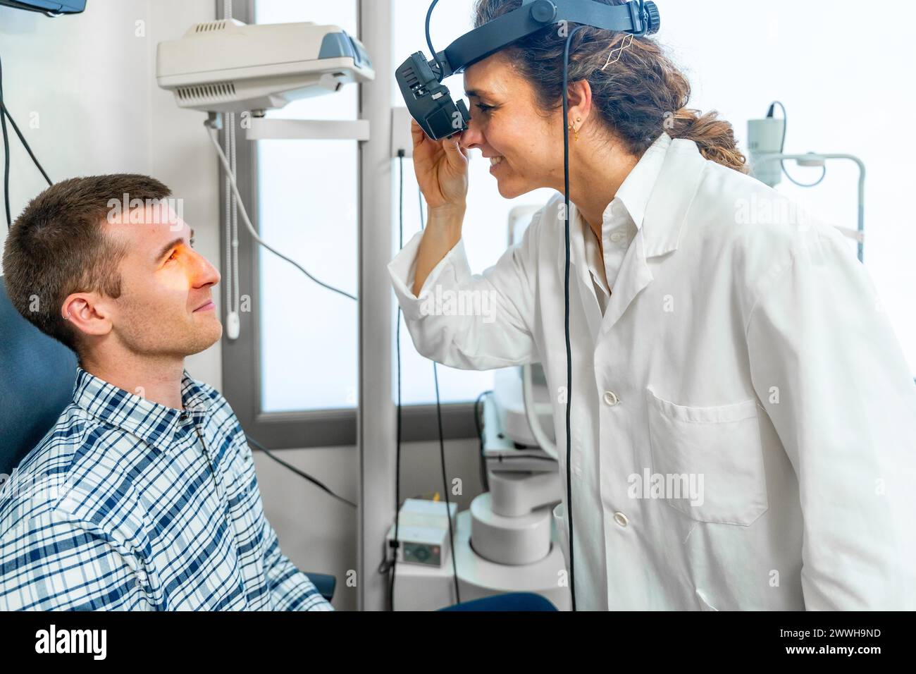 Female ophthalmologist checking the retina of a patient using the light of a retinoscope Stock Photo