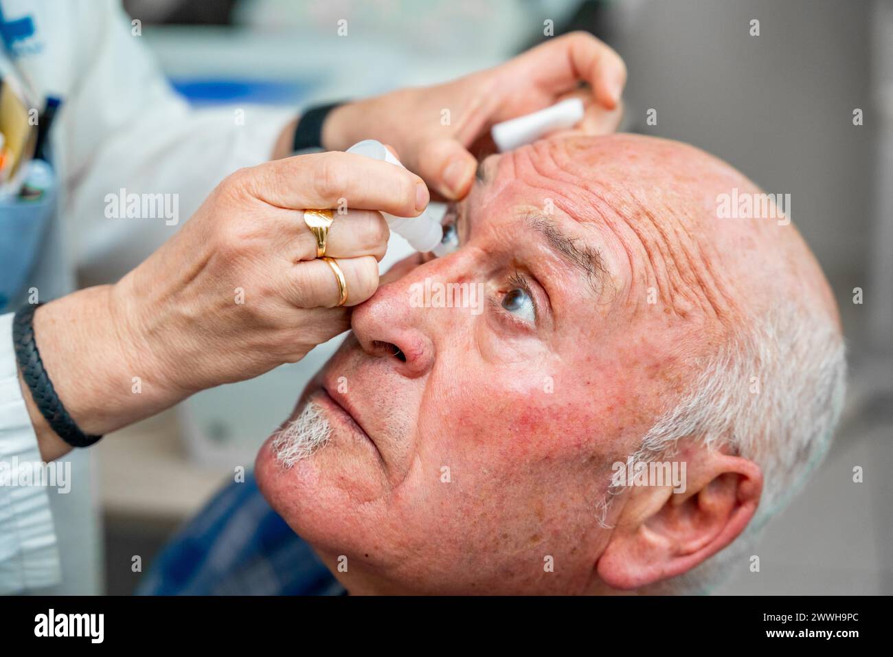 Ophthalmologist pouring drops to dilate the pupil to a man during a glaucoma examination test Stock Photo