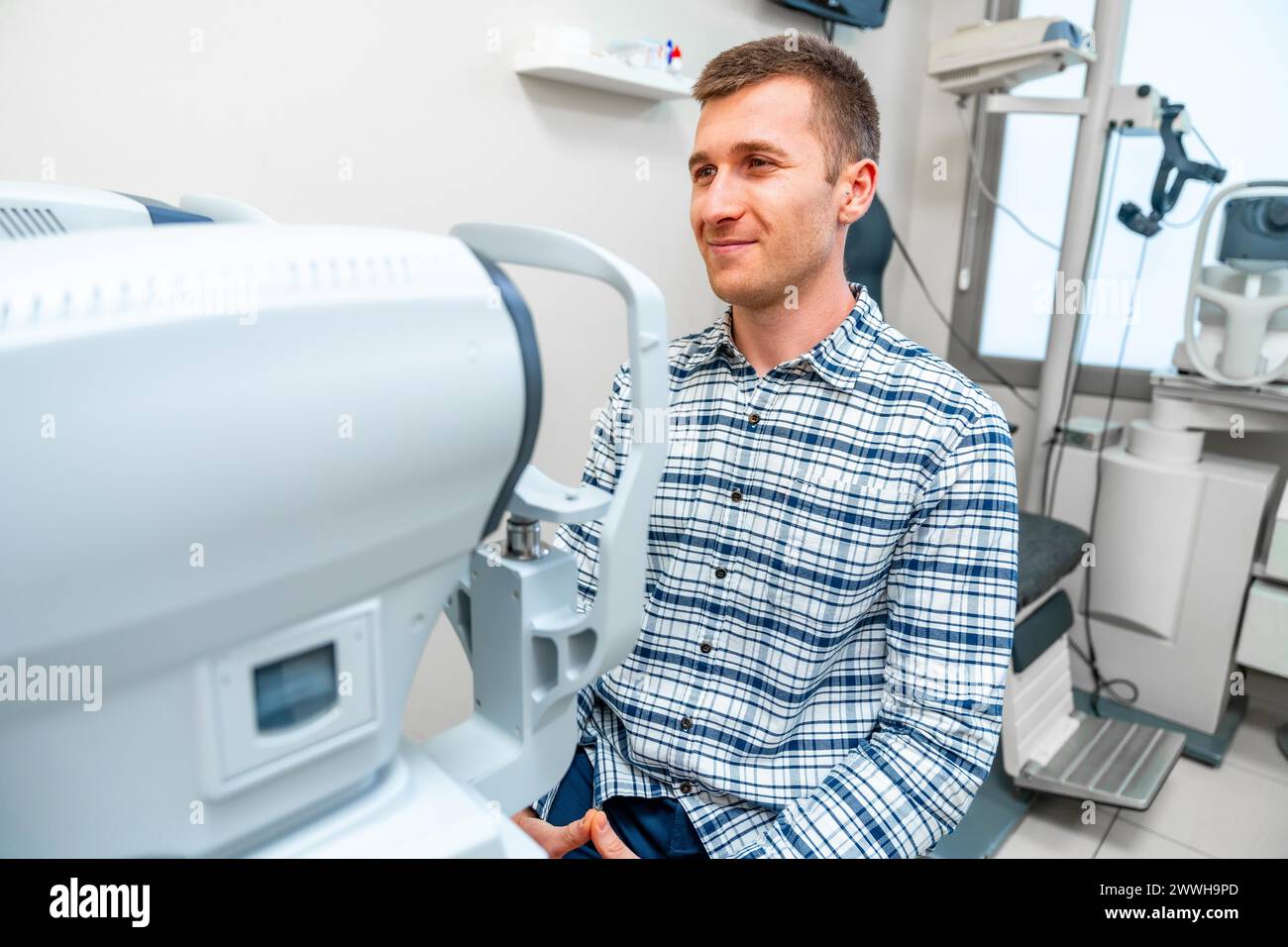 Man about to scan her eye in scanner machine in a clinic Stock Photo