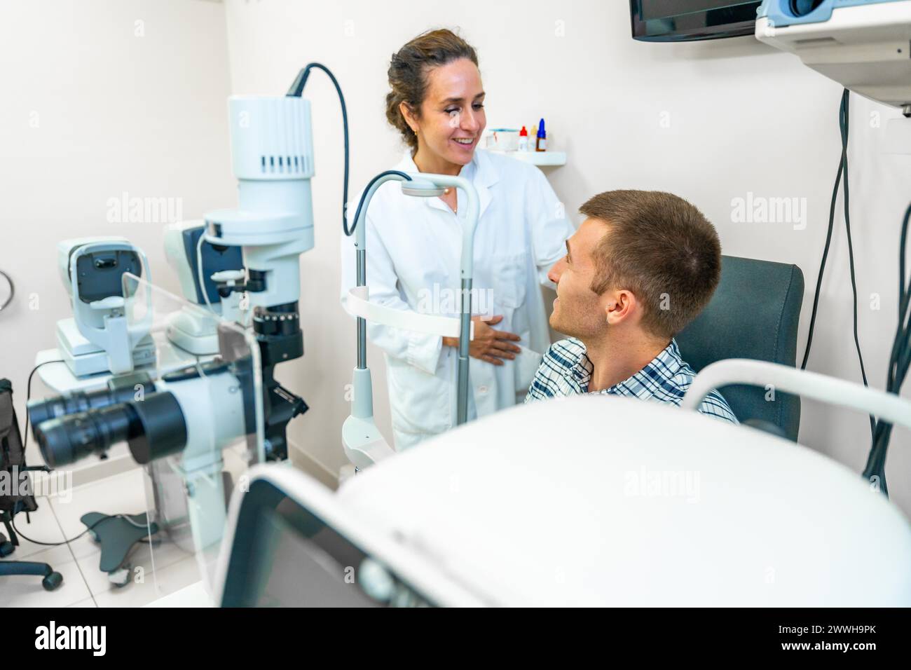 Female optometrist talking with male patient in the clinic Stock Photo