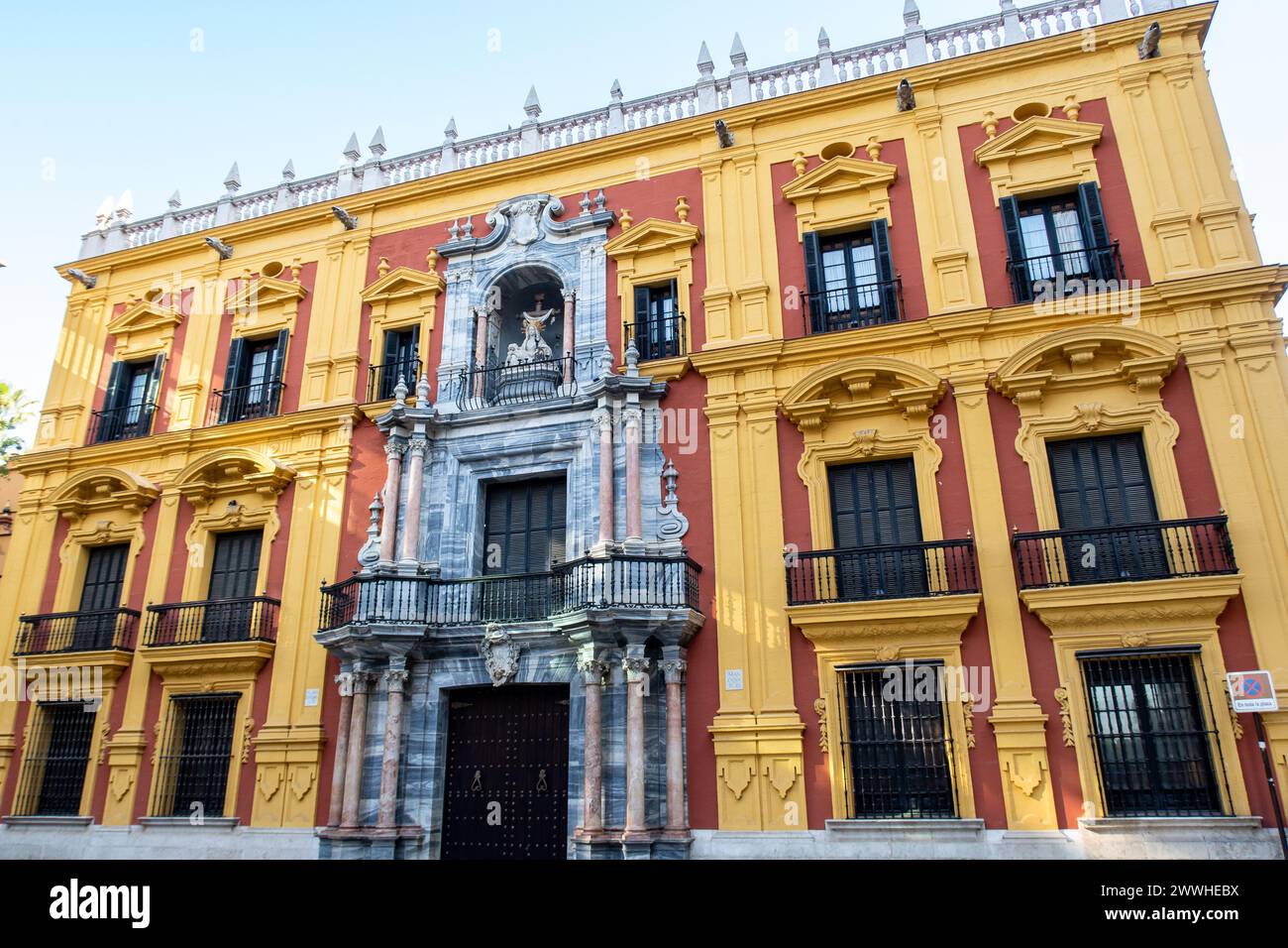 Episcopal Palace (Palacio Episcopal, Bishops Palace) on Obispo Square, Malaga, Andalusia, Spain with colorful yellow and red Spanish Baroque facade. Stock Photo