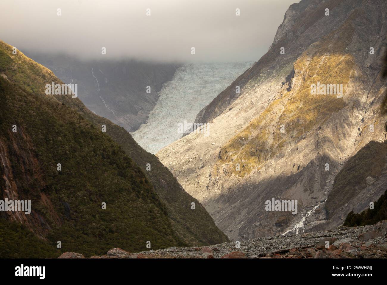 Cloud obscures part of the shrinking Fox glacier on the west coast of the South Island of New Zealand. Stock Photo