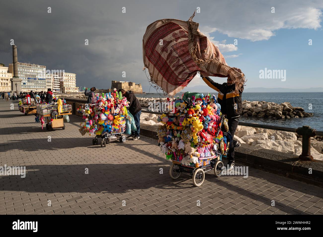 Storm approaches Naples coast causing street vendor to cover his stall catching his cover in the wind Stock Photo