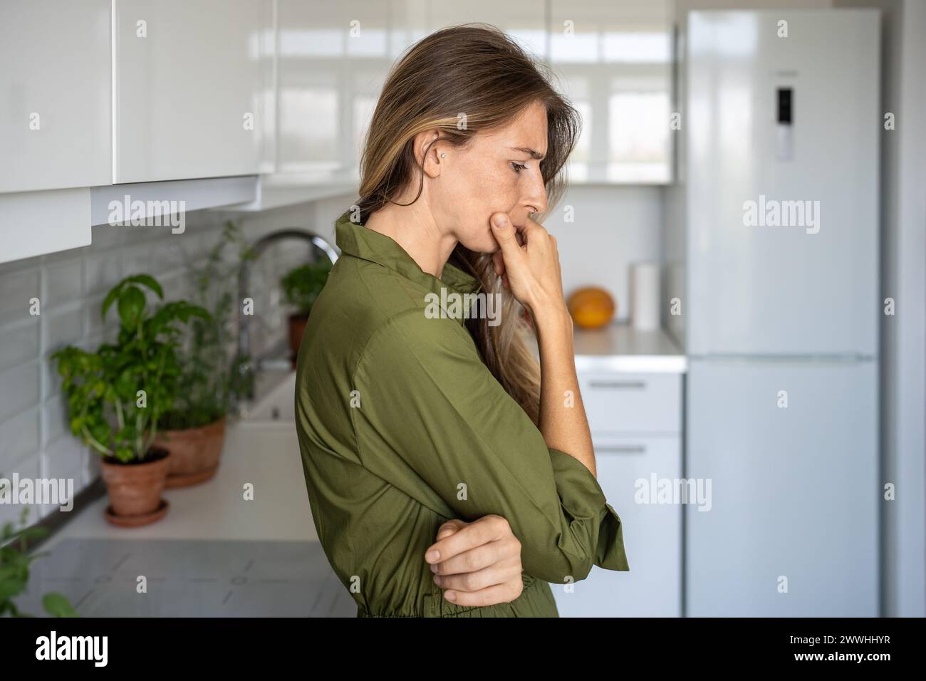 Depressed frustrated middle aged woman thinking about difficult problems standing at home in tension Stock Photo