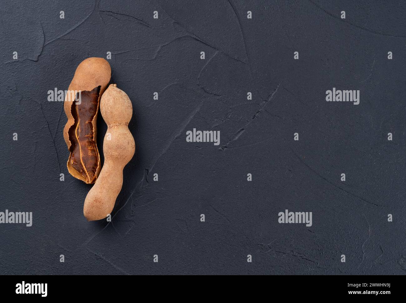 Tamarind fruit in shell on empty dark background, top view. Copy space Stock Photo