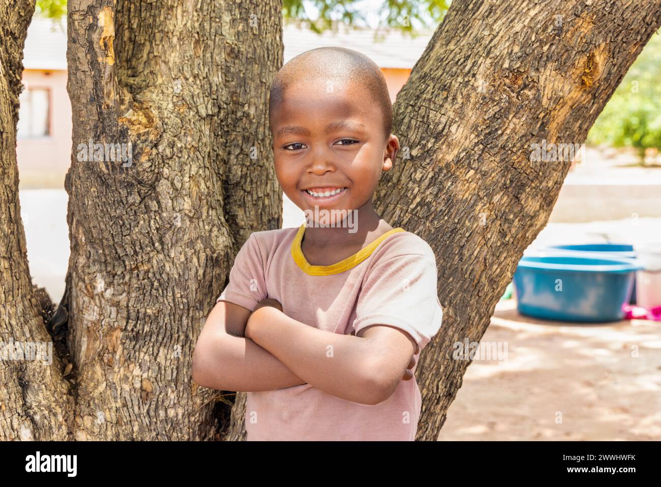 village african boy standing in front of a tree, in the yard Stock Photo