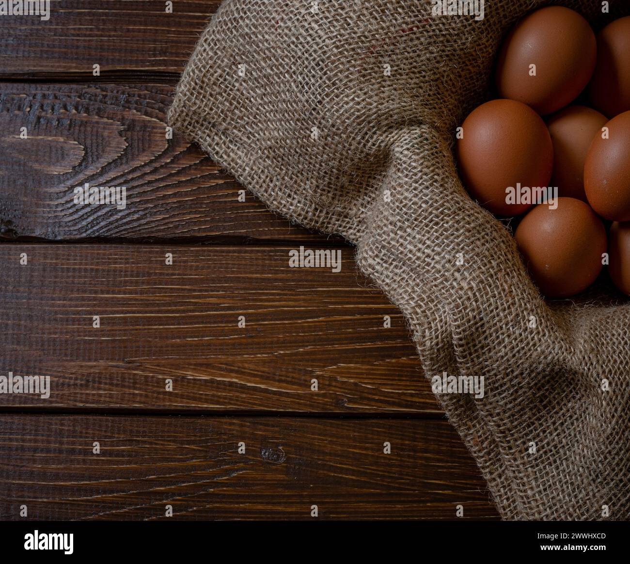 Fresh chicken eggs in a basket on a sack, egg day, wooden table.Selective focus Stock Photo