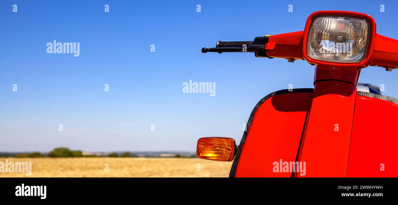 classic scooter on spacious field of drying grass in the heat of the summer with copy space on left classic scooter on s classic scooter on spacious f Stock Photo