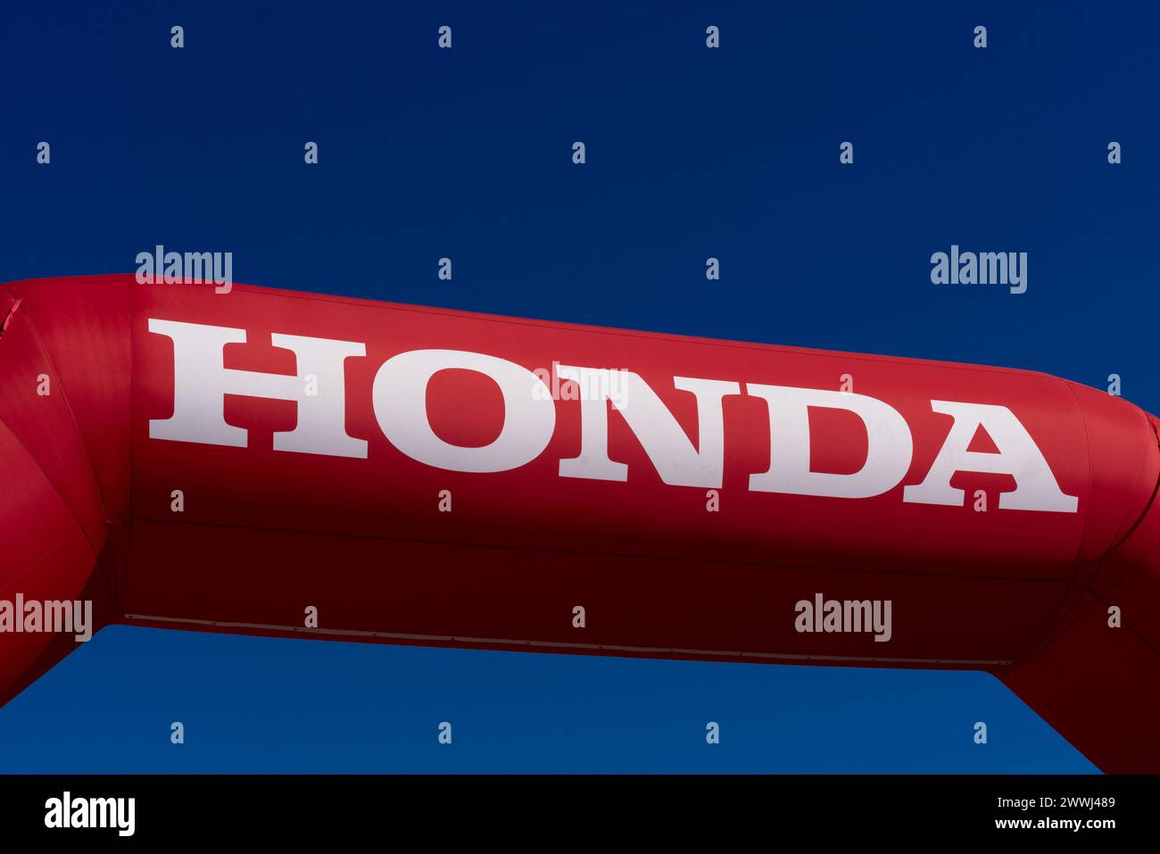 Italy - March 24, 2024: Honda logo on red inflatable sign on blue sky, Honda Motor Co. is Japanese multinational company that manufactures automobiles Stock Photo