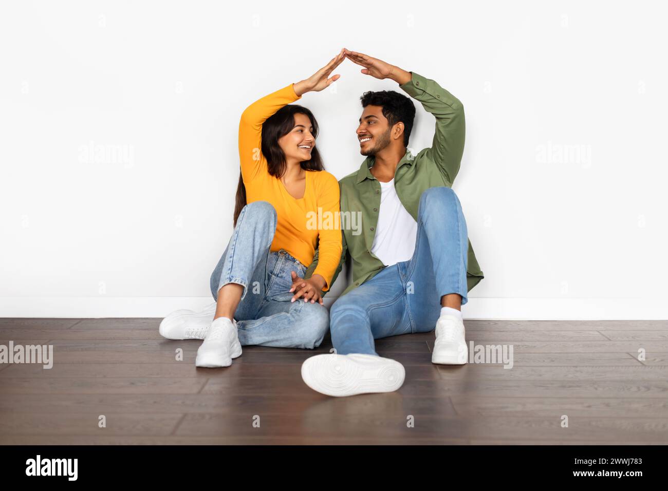 Happy Indian couple sitting and making roof with hands Stock Photo - Alamy