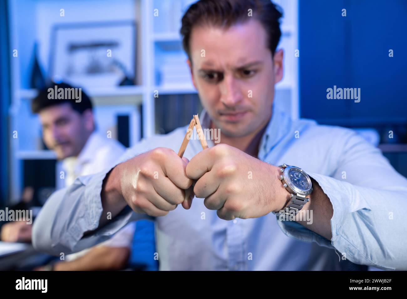 Stressful burnout of businessman destroying pencil for venting emotion in overwork load at night time, supported by business partner to solve issue Stock Photo