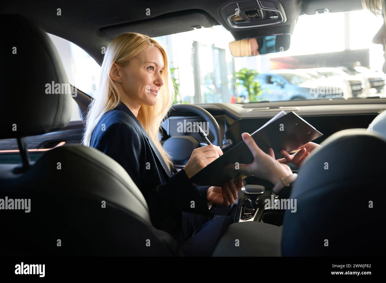 Lady signs a contract in a car Stock Photo - Alamy