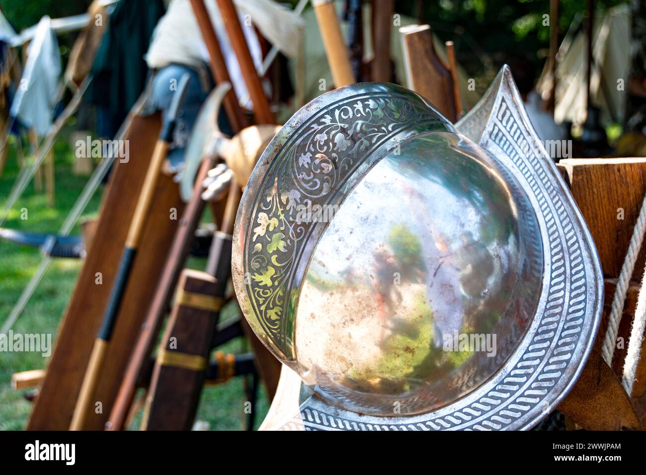 Worn metal Spanish style military helmet with medieval weapons in the background Stock Photo