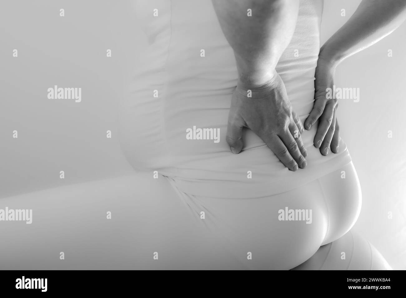 Description Pregnant mother with baby bump feels back pain and holds