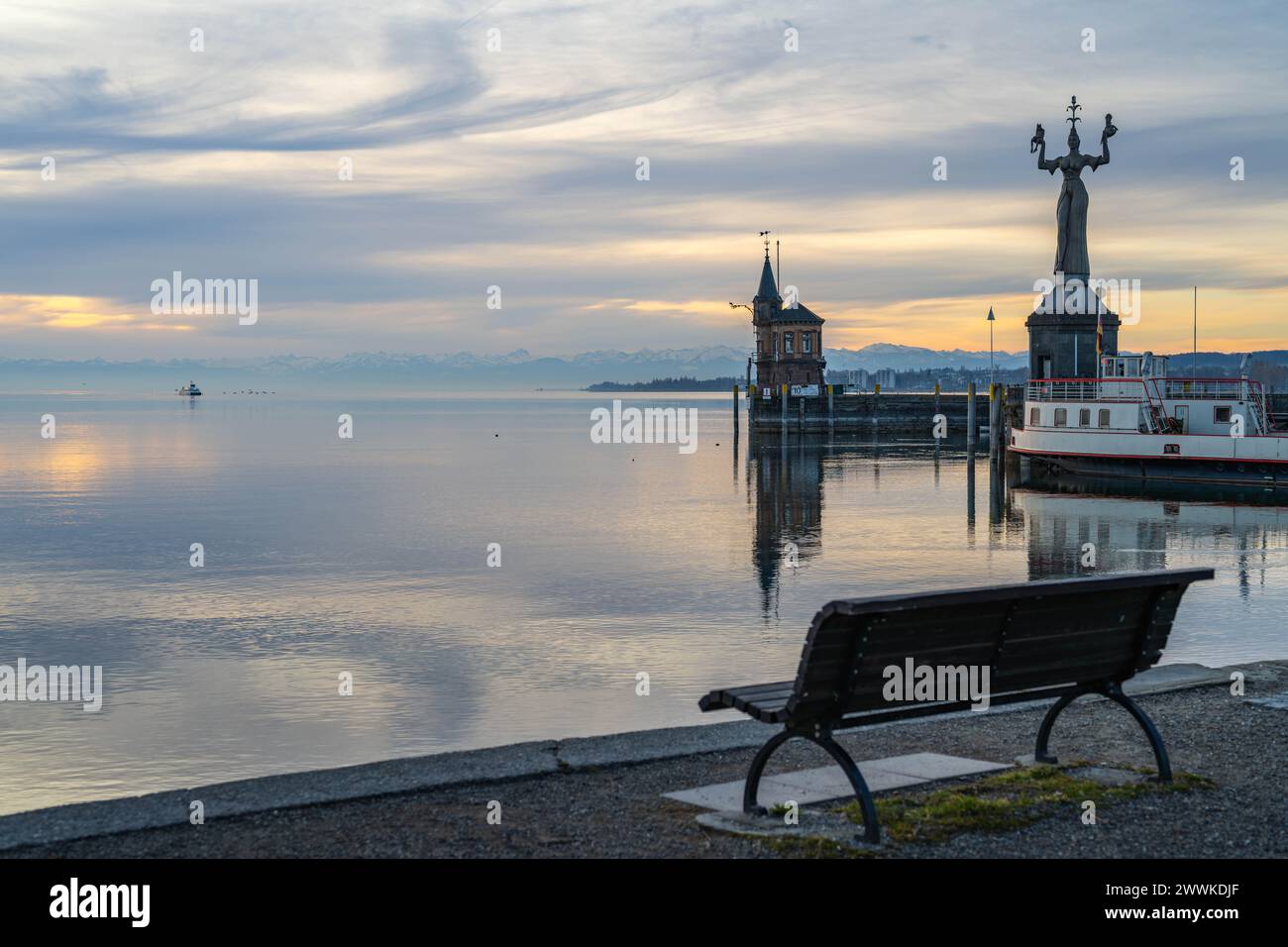 Beschreibung: Blick auf die Hafeneinfahrt von Konstanz mit der Imperia-Statue und der Katamaran-Fähre auf dem See und den schneebedeckten Alpen am Hor Stock Photo