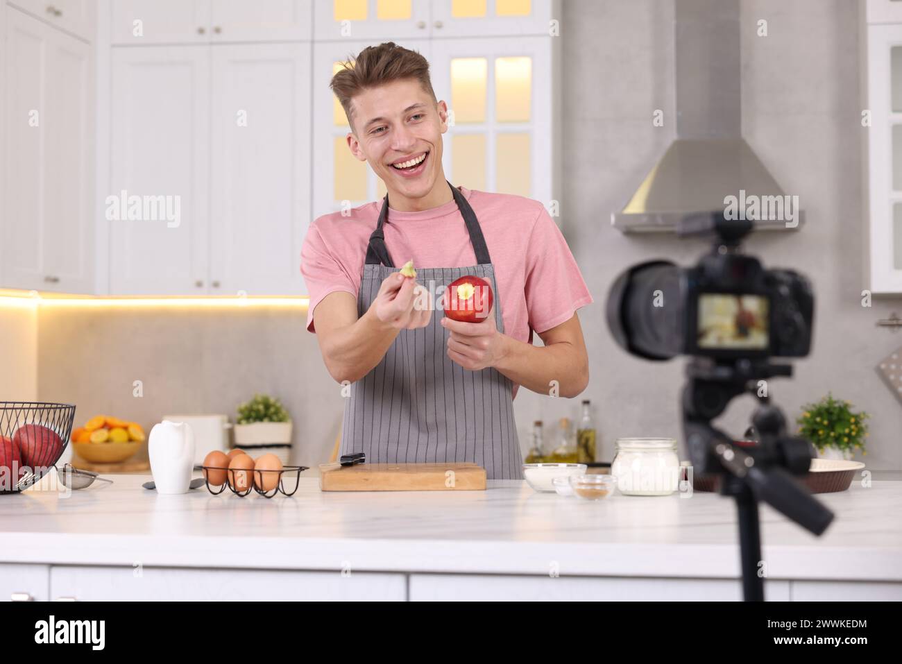 Smiling food blogger explaining something while recording video in kitchen Stock Photo
